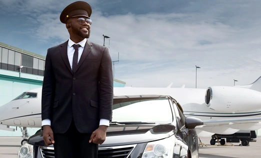 Professional chauffeur and luxury car at an airport hangar, highlighting the high-end experience of booking a Smyrna airport limo service.